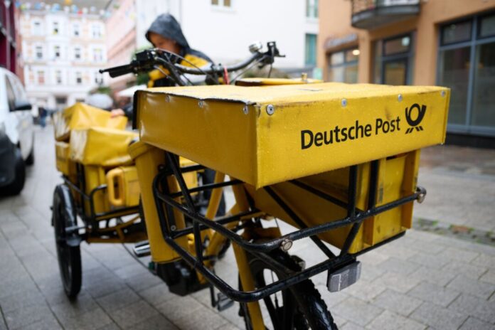 Briefporto und Briefversand Eine Postbotin bei der Arbeit.